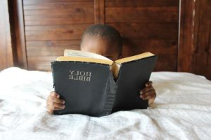 Child reading Scripture in bed